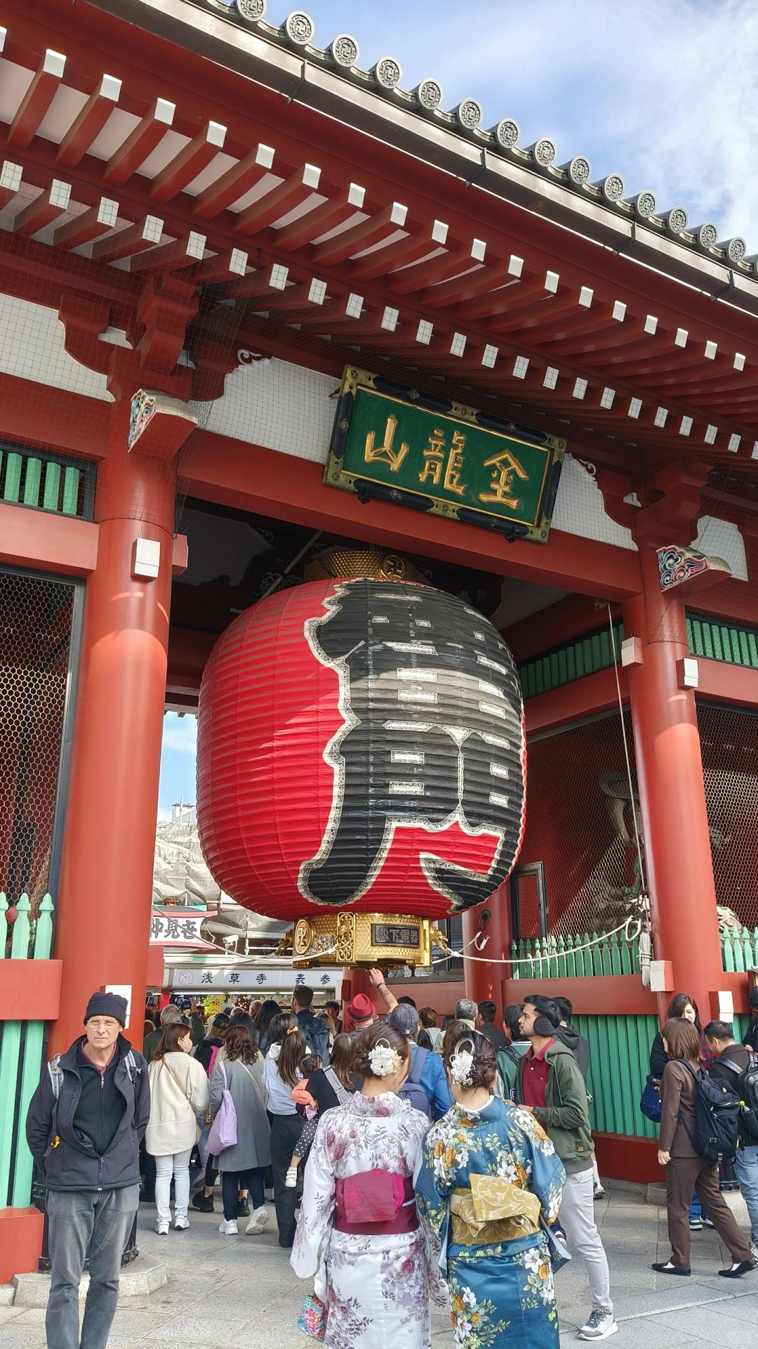 Tokyo-Sensoji Temple crowded with people has red beams and black tiles next toAsakusa Shrine