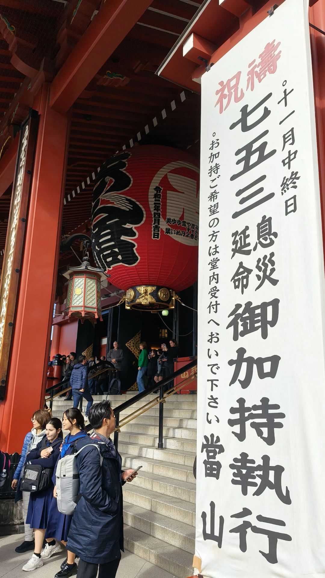 Tokyo-Sensoji Temple crowded with people has red beams and black tiles next toAsakusa Shrine
