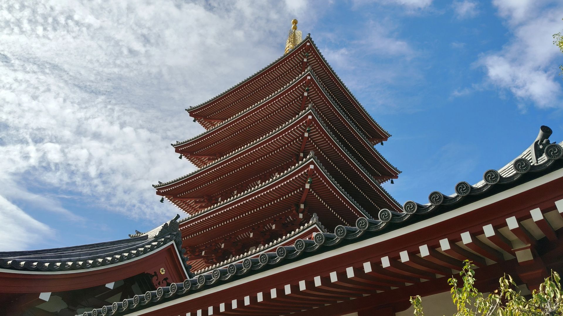 Tokyo-Sensoji Temple crowded with people has red beams and black tiles next toAsakusa Shrine