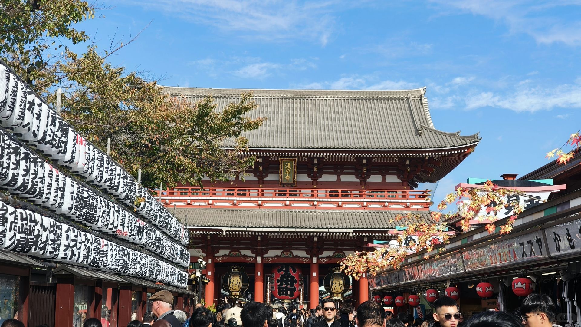 Tokyo-Sensoji Temple crowded with people has red beams and black tiles next toAsakusa Shrine