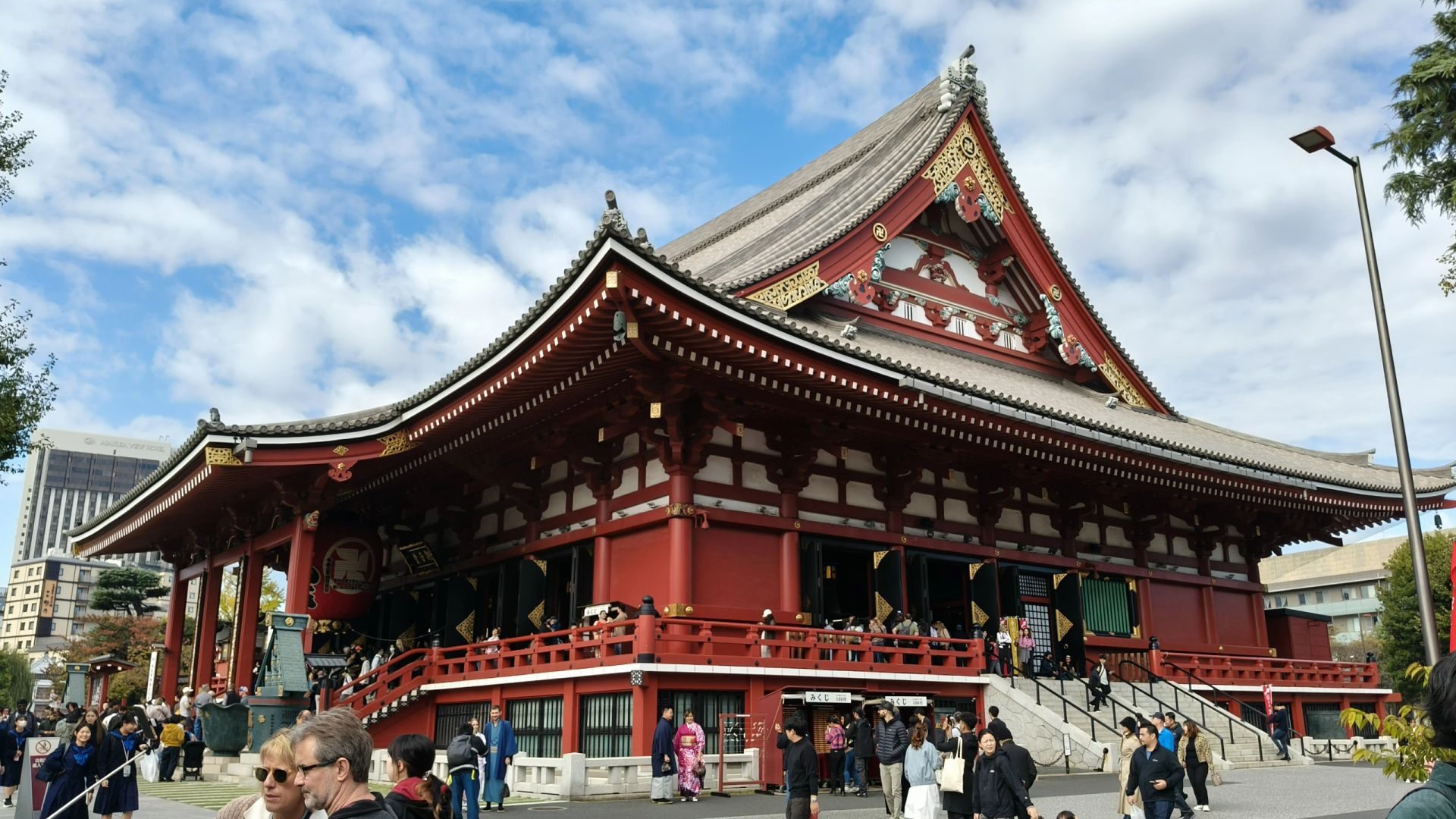 Tokyo-Sensoji Temple crowded with people has red beams and black tiles next toAsakusa Shrine