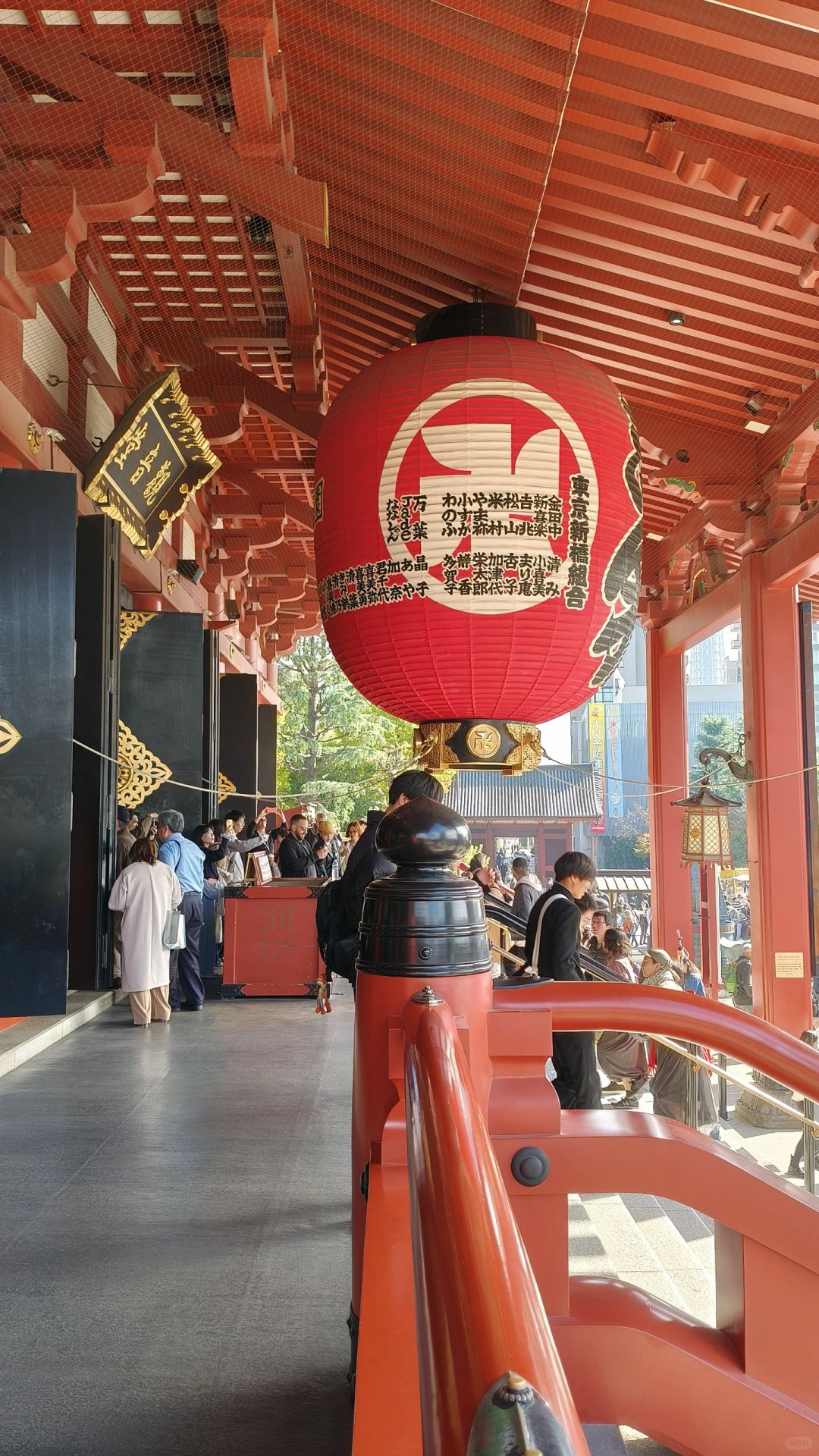 Tokyo-Sensoji Temple crowded with people has red beams and black tiles next toAsakusa Shrine